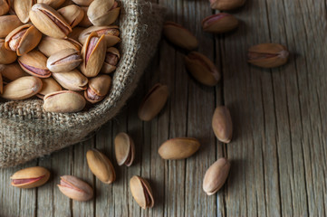 Pistachio in nutshell in burlap sack or sackcloth on wooden rustic backdrop, composition of pistachios great for healthy and dietary nutrition. Concept of nuts
