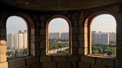 view from a broken window of the city with panel buildings
