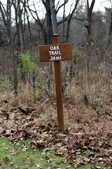 A brown wooden trail sign on the trail and a close up view.