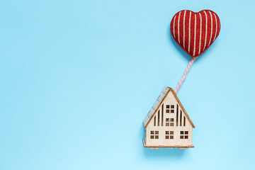 flat lay top view, wooden house with heart flying on a balloon in the shape of a heart, concept of family, home, gift, valentine's day on pastel background