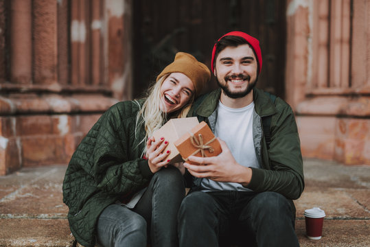 Portrait of beautiful cheerful girl with present having date with boyfriend. They looking at camera and smiling