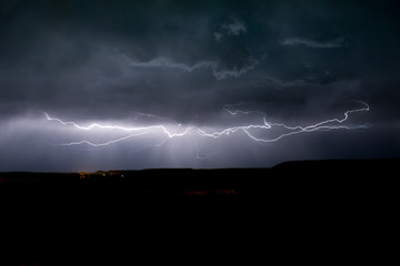 Naklejka na ściany i meble A horizontal lightning bolt is visible below the clouds of a thunderstorm in eastern Montana