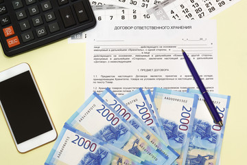 Obraz premium The form of the document with the Russian text of the contract of safekeeping. Calculator, smartphone and money on the table