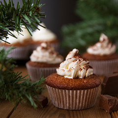 Chocolate cupcakes with whipped cream on rustic wooden table. Homemade dessert. Square image.