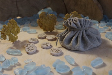 Wooden handmade witch runes with a linen pouch, blue cristals and yellow flowers in a rustic style