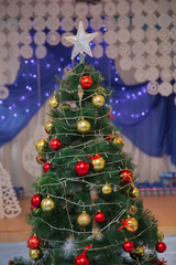 House, white deer, curtain . Winter holiday concept, decorated Christmas tree in the interior.Christmas tree star light on black background . Joyful studio shot of a Christmas tree with ornaments .