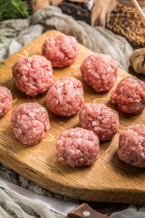 Raw meatballs on the wooden cutting board.