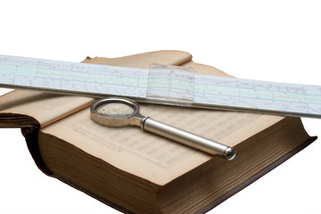 Handbook of mathematics, magnifying glass and a slide rule isolated on white background. Blurred text in the book.