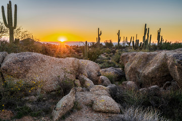 The sun peeks over the mountains, illuminating the desert