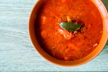 Traditional Ukrainian Russian vegetable borscht on red bowl. Flat lay. Top view. Wooden background