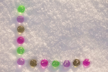 Colorful glass christmas balls on the shining snow background.