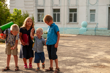 Children return to school. beginning of new school year after summer holidays. Boys and girl with school bags play among flowers near school building. Education for kindergarten and preschool children