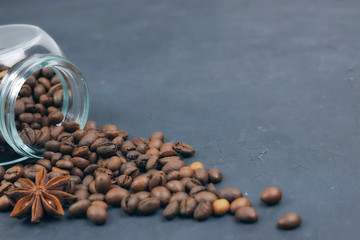 roasted coffee beans poured from a glass jar. angular placement of the coffee object. on dark...