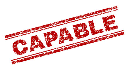CAPABLE seal stamp with corroded effect. Red vector rubber print of CAPABLE tag with corroded texture. Text tag is placed between double parallel lines.