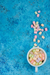 white cup with coffee on the table. marshmallows view from above. place for text. Abstract background.