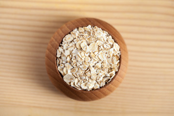 Oat flakes in a wooden bowl on the wooden table