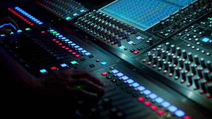 Hand of soundman on the mixing console during a concert