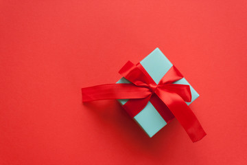 Blue gift tied with red ribbon on red background