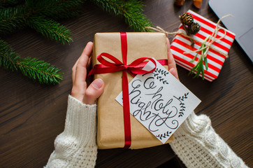 Woman holding in hands christmas present with red ribbon. Xmas concept. Eye bird view.