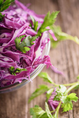 Shredded red cabbage with parsley in a transparent bowl on a dark wooden background, Vegetarian healthy food.