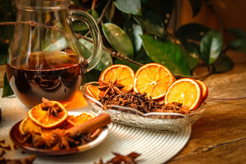 Beautiful composition with anise, cloves, cinnamon stick and powder, tea and dried orange. Wooden table, rustic background and candle light. Close-up.