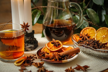 Beautiful composition with anise, cloves, cinnamon stick and powder, tea and dried orange. Wooden table, rustic background and candle light. Close-up.