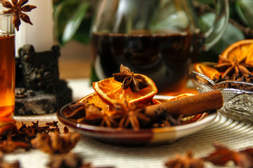 Beautiful composition with anise, cloves, cinnamon stick and powder, tea and dried orange. Wooden table, rustic background and candle light. Close-up.