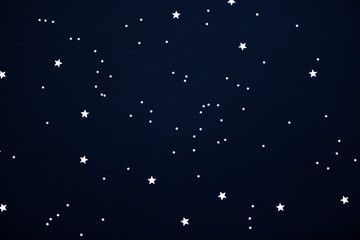 Confetti in shape of stars on dark background. Night, space or universe concept.