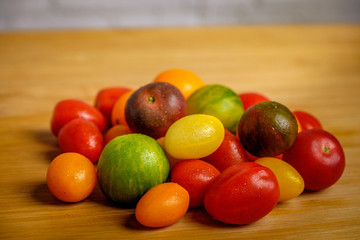 Red, green, yellow and orange cherry tomatoes on wooden desk