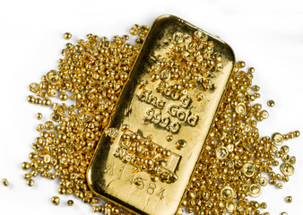 Gold bar in a pile of gold granules. Isolated on a white background.