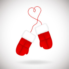 A pair of red warm mittens with white fluffy fur on a striped lace. Traditional winter accessory isolated on white background.