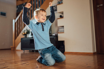 Five years old  cute boy shows joy after scoring a goal in the living room during sunny day