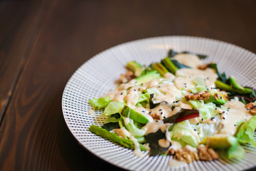 Close up Healthy salad with avocado , walnuts and grilled asparagus . Vegan food on dark wooden table.