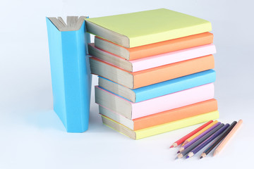 colored pencils and stack of books on white background. photo wi