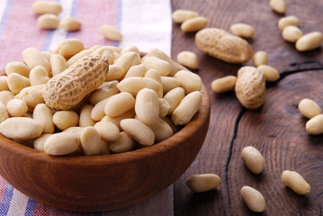 Raw peanut peeled in a bowl on a wooden background.