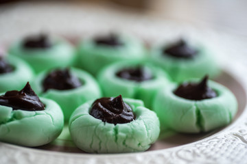 plate of mint green christmas holiday cookies with chocolate ganache center on decorative plate.  selective focus, shallow depth of field