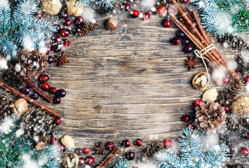 Christmas background with festive decorations, winter spices,  cranberries, nuts and blue fir branches,