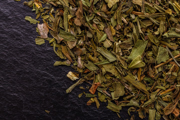 dried tarragon and essential oil on a dark stone background