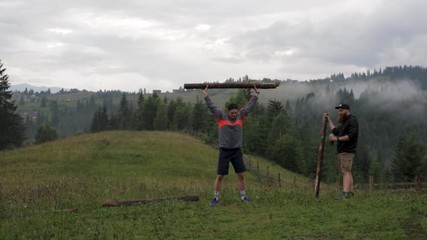 man doing workout exercise with big log in the mountains. Sport and workouts outdoors