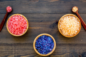 Colorful bath salt pink and blue on dark wooden background top view copy space