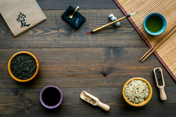 Chinese traditional symbols concept. Tea, rice, hieroglyph love, bamboo table mat, chopsticks, soy sause on dark wooden background top view frame space for text
