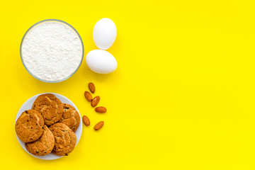 Ingredients for homemade cookies. Fresh cookies near flour, eggs on yellow background top view copy space