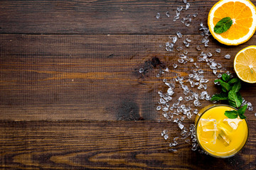 Orange juice and citrus cocktails. Juice in glass near cut orange and lemon, crushed ice, green mint on dark wooden background top view space for text