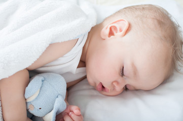 Beautiful baby boy laying down in his bed and sleeping. Close up.