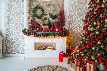 White room interior in red tones with New Year tree decorated, present boxes and artificial...