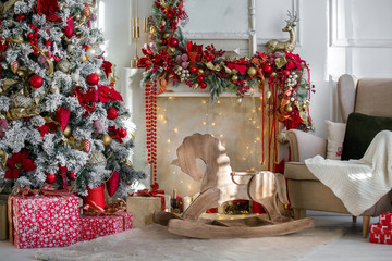 White room interior in red tones with New Year tree decorated, present boxes and artificial fireplace