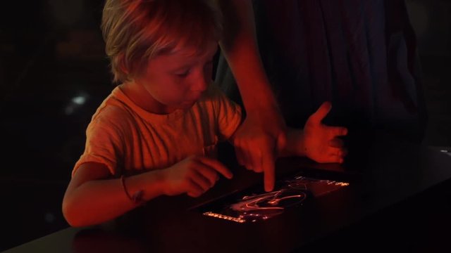 Little boy uses a table pc with an astronomical zodiak map. Children education concept.