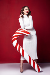Sexy pretty lady fashion model beautiful woman wear style skinny knitted white color dress celebration happy holidays merry Christmas Eve new year party hold candy cane caramel brunette makeup. © indiraswork
