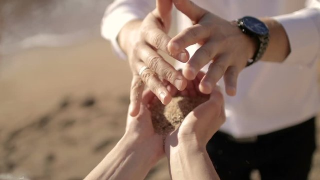 The man pours sand in woman's hands