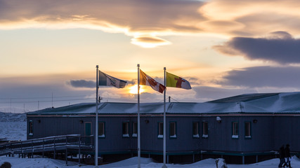 Flags above snowy Iqaluit town center in golden winter light, Nunavut © Jef